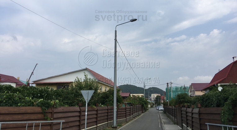 На фото изображена часть системы освещения коттеджного поселка. Используемые конструкции часто используются для строительства инженерной инфраструктуры после обустройства улицы. Благодаря использованию СИП на арматуре не нужно разрушать тротуар или дорогу, чтобы проложить провод. 