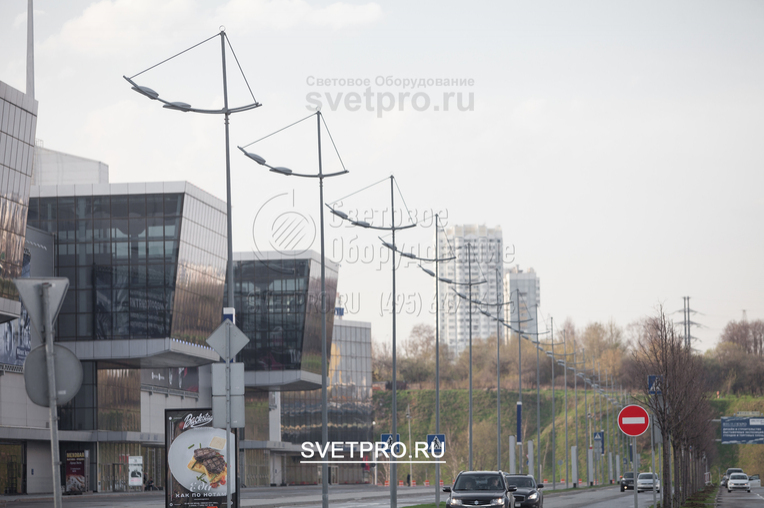 На изображении представлены опоры модификации ОГК, на которых установлены красивые кронштейны. Они имеют консоли, изогнутые под определенным радиусом и соединенные поперечными элементами, на которых закреплены светильники.