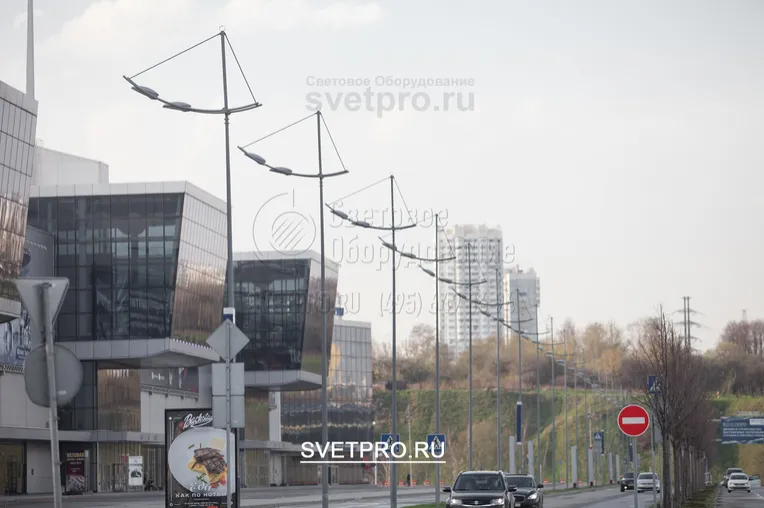 На изображении представлены опоры модификации ОГК, на которых установлены красивые кронштейны. Они имеют консоли, изогнутые под определенным радиусом и соединенные поперечными элементами, на которых закреплены светильники.