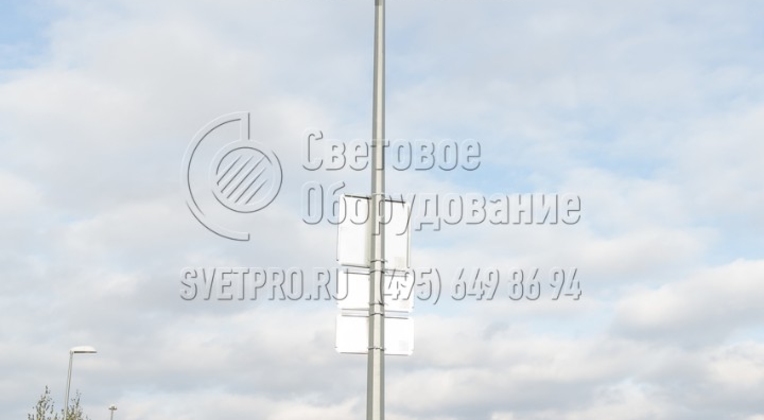 Изображенная на фото опора разработана как универсальная опора освещения для решения разнообразных задач в сфере освещения. В этом варианте на ее верхушке установлены прожекторы направленного света. А на корпус с помощью накладных кронштейнов установлены дорожные знаки. 