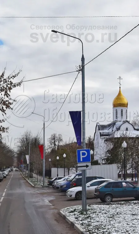 На фото приведен пример использования трубчатой опоры. Хотя она и является несиловой, но выдерживает вес от тяжелого светового прибора с кронштейном, подвешенных проводов и дорожного знака. Кроме того, на корпусе закреплена декоративная конструкция для крепления баннеров. 