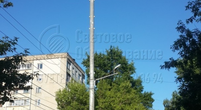 В представленном на фотографии варианте трубчатая осветительная опора используется одновременно в качестве громоотвода. На оголовке корпуса расположен штырь молниеприемника, а система заземления присоединяется к усиливающей косынке фланца в нижней части ствола. 