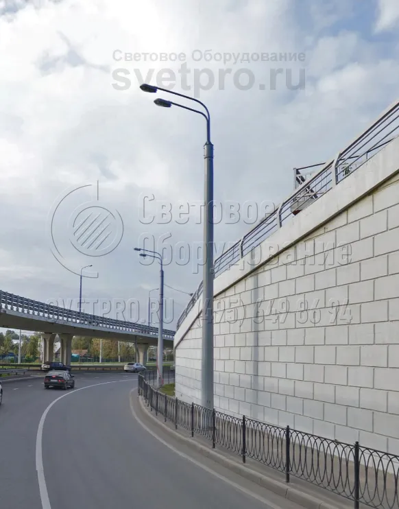 В классическом варианте к силовой опоре подводить провода можно по воздуху. Однако для улучшения внешнего вида улиц инженеры прибегают к подземному подключению, как в варианте на фотографии. На верхушке ствола закреплен кронштейн с двумя рожками, который крепится за обечайку. 