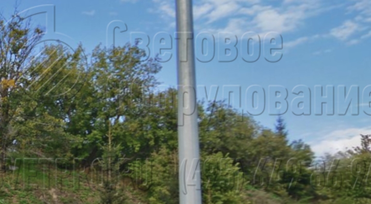 Опора на фотографии отличается повышенной несущей способностью. Поэтому на ее верхушке установлен кронштейн с двумя рожками, размещенными один над другим. Световые приборы создают яркое заливающее освещение, которого хватает для освещения тротуара и автомобильной дороги. 