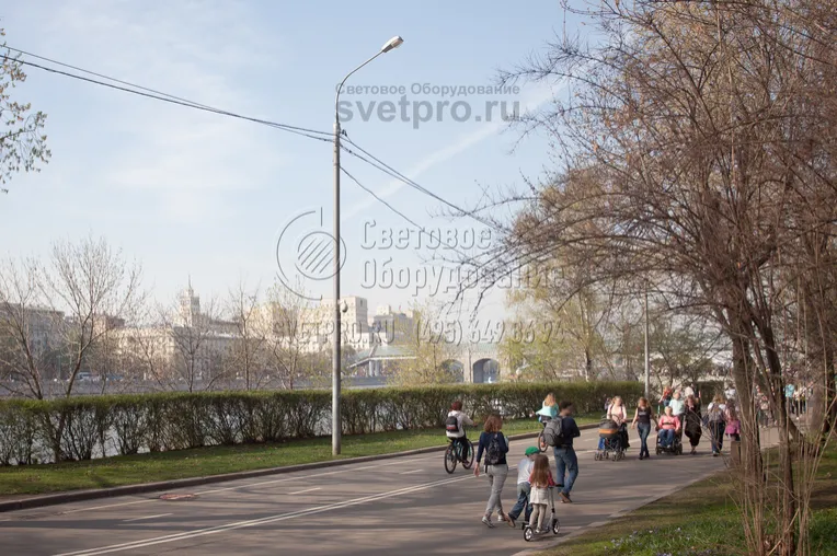 На фото изображена опора типа СФ, которая используется для освещения парка. На ней, помимо светильника, закреплена видеокамера и консольный светильник. Использование одной универсальной конструкции позволяет сократить их число в парке и улучшить внешний вид места отдыха людей. 
