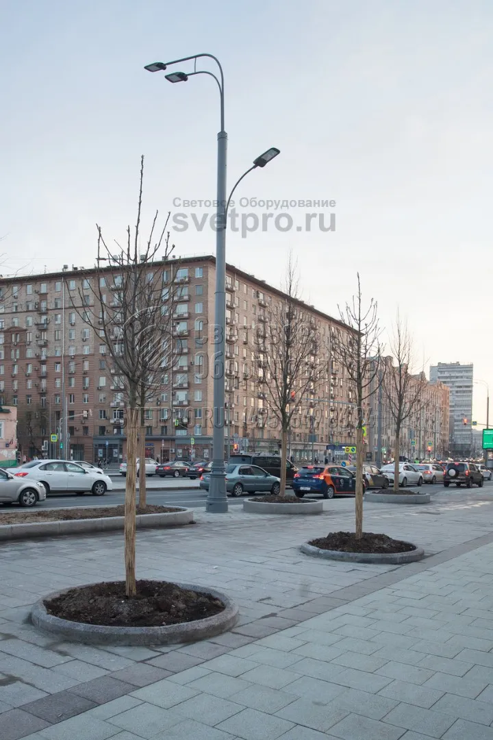 На этом фото приведен пример использования трубчатой опоры, которая одновременно освещает проезжую часть с одной стороны корпуса и тротуар с другой. Используется два кронштейна, один из которых закреплен прямо на стволе. Максимальная нагрузка на оголовок может составлять до 700 кг.