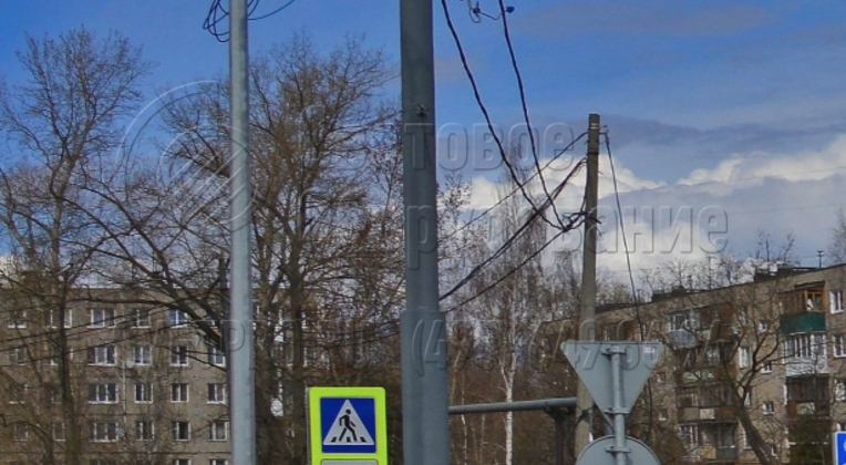 Опора контактной сети на фото установлена в грунте прямостоечным способом. Для этого используется хвостовик. Он погружается в землю в предварительно пробуренный котлован. Для фиксации хвостовик в котловане заливается бетонным раствором. Закладная деталь фундамента не используется. 
