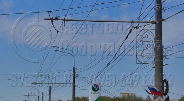 Ствол на фото предназначен для крепления консоли с контактными проводами троллейбусов. Однако одновременно с этим к нему подвешено огромное количество силовых линий, установлены мощные приборы освещения, дорожный знак и декоративные элементы для украшения улицы. 