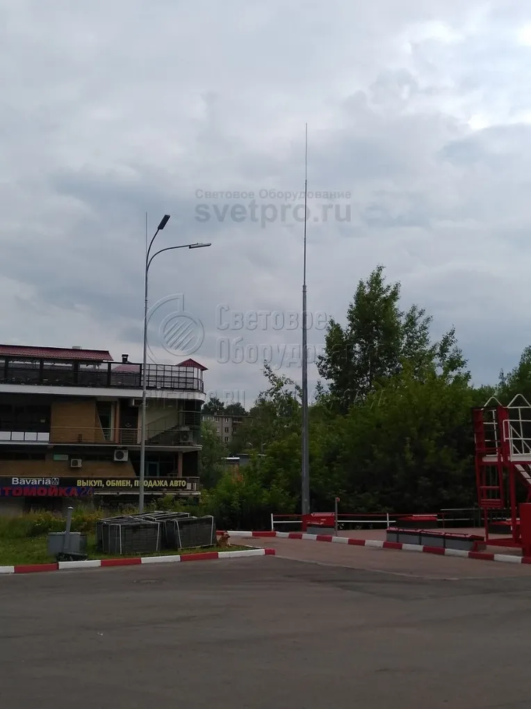 На этом изображении представлено два вида молниеотводов. Один выполнен по классической схеме и состоит из корпуса, на который прикручен штырь молниеприемника. Второй представляет собой комбинацию молниеотвода и опоры, на которой установлены два светодиодных светильника уличного освещения.