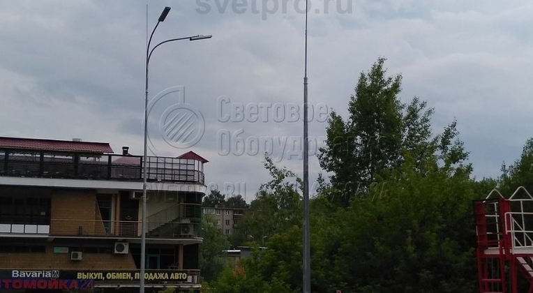 На этом изображении представлено два вида молниеотводов. Один выполнен по классической схеме и состоит из корпуса, на который прикручен штырь молниеприемника. Второй представляет собой комбинацию молниеотвода и опоры, на которой установлены два светодиодных светильника уличного освещения.